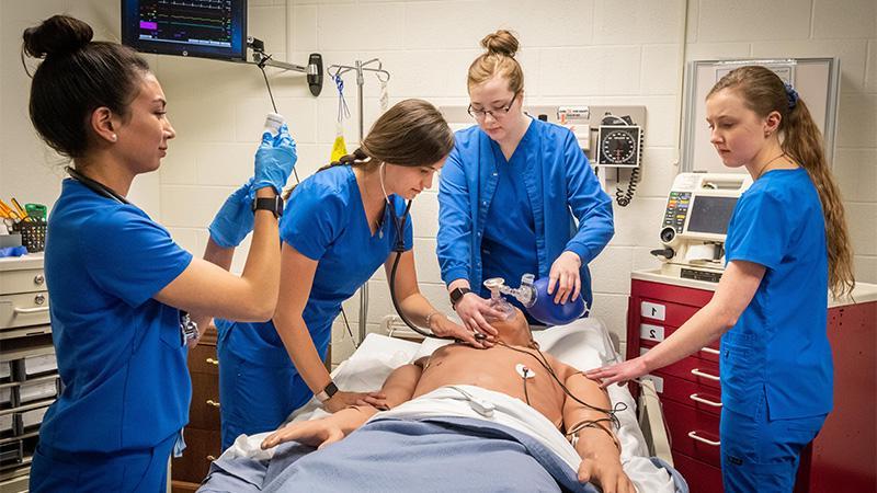 护理 Students standing around medical human dummy